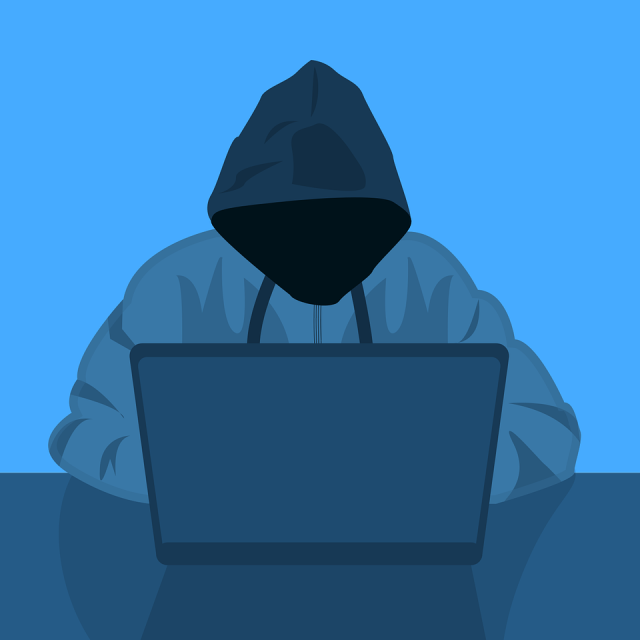 hooded person in front of computer